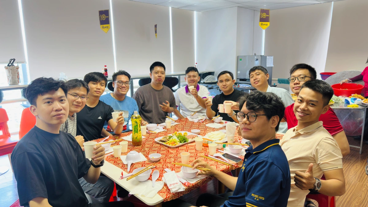 They are smiling and holding cups, with food and drinks